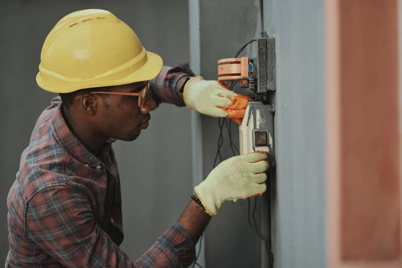 A field technician in a hard hat checking a work order on a phone